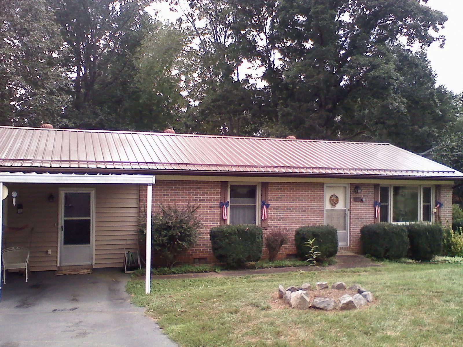 Bronze metal roof and carport on a brick ranch home — Roof Repair work by our crew in Otis